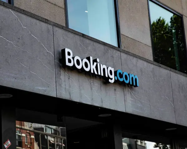 Logo Booking.com na szarym, kamiennym budynku. Planujesz podróż i szukasz najlepszych ofert? Z booking cashback Twoje wakacje będą tańsze!