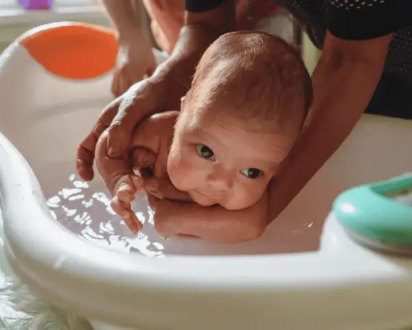 Delikatne kąpiel noworodka w wanience. Czy przy gorączce można kąpać dziecko? Tak, ale w letniej wodzie.