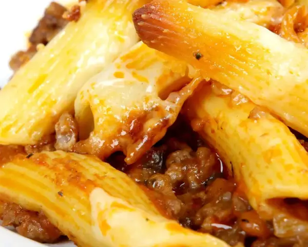 Macarrones con carne y queso fundido, cubiertos con salsa de tomate.