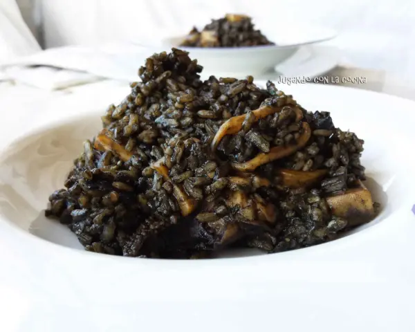 Un plato de arroz negro con trozos de calamar, servido en un cuenco blanco.
