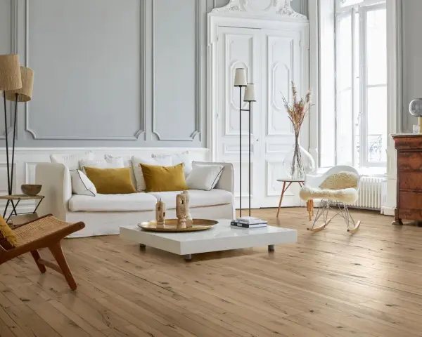 Stilvolles Wohnzimmer mit hellem Parkettboden, der durch regelmäßige Parkett Pflege glänzt. Gemütliche Couch, Sessel und ein moderner Couchtisch.