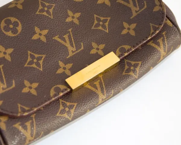 Zbliżenie na brązową torebkę Louis Vuitton z monogramem i złotym zapięciem.