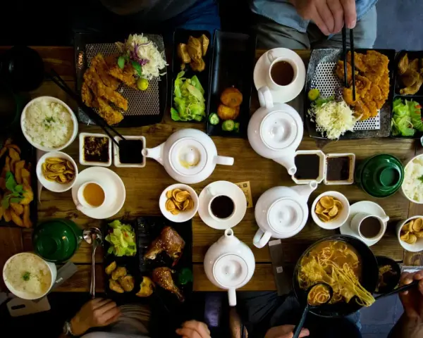 Mesa llena de platos asiáticos, teteras y tazas. Una experiencia culinaria en un restaurante sensorial.