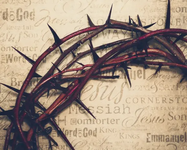 Dornenkrone auf Pergament mit Titeln wie "Jesus", "Messiah", "Savior". Sie symbolisiert die tiefe Jesus Christus Bedeutung und sein Leiden.