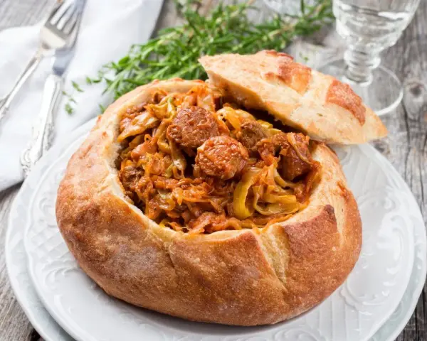 Bigos staropolski w chlebie, sycące danie z kapusty i kiełbasy, idealne na zimowe wieczory.