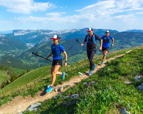 Trzy osoby uprawiające speed hiking na górskim szlaku, ciesząc się pięknymi widokami.