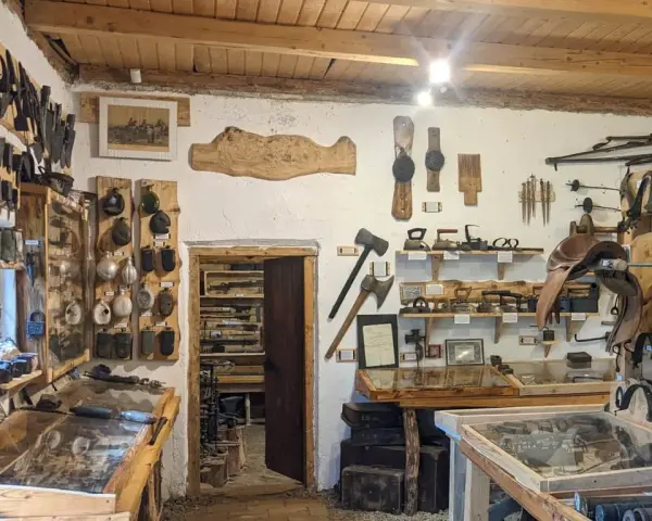 Wnętrze muzeum historii Bieszczad. Eksponaty to narzędzia, broń, siodła i przedmioty codziennego użytku.