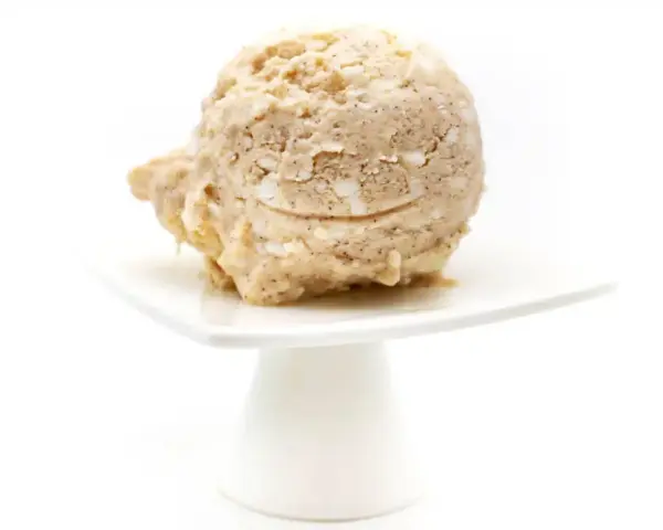 Eine Kugel Milchreis Eis auf einem weißen Teller. Cremig und mit Stückchen, ein Genuss!
