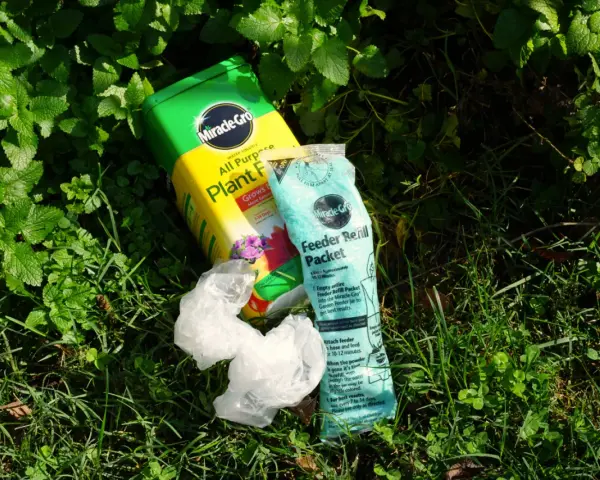 Miracle-Gro plant food and feeder refill packet lie on grass. While not inherently toxic, proper use is key to avoid harming plants.
