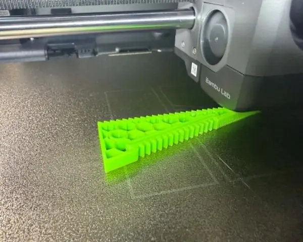 Drukarka 3D tworzy zielony obiekt z filamentu TPU, pokazując jego elastyczne właściwości.