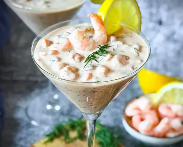 Ein cremiger Shrimp Cocktail in einem Martiniglas, garniert mit Dill und Zitrone. Ein köstlicher Genuss!