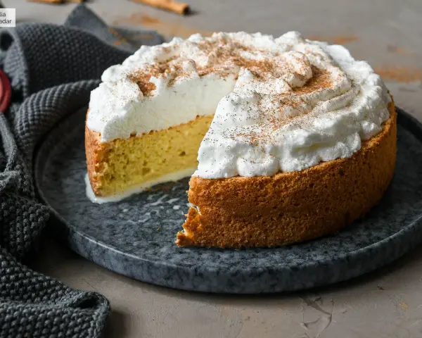 Tarta tres leches esponjosa, cubierta de merengue y espolvoreada con canela. Se ve deliciosa y lista para disfrutar.