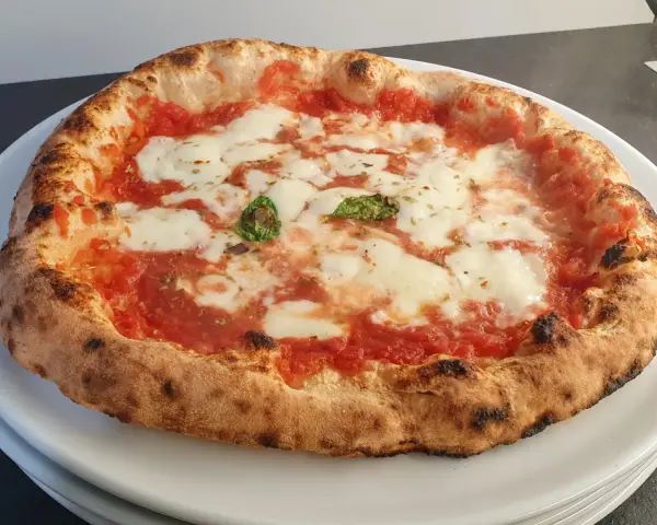 Pizza a lunga lievitazione con pomodoro, mozzarella filante e basilico fresco. Croccante fuori, soffice dentro, un vero capolavoro.