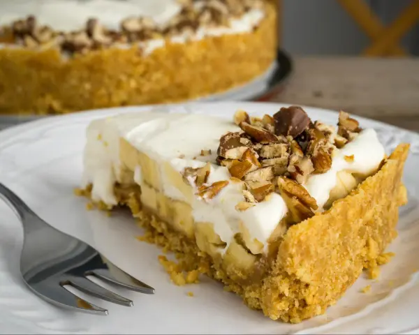 Pyszny kawałek Banoffee Pie z bananami, kremem i orzechami. Idealny na deser, gdy masz ochotę na coś słodkiego.