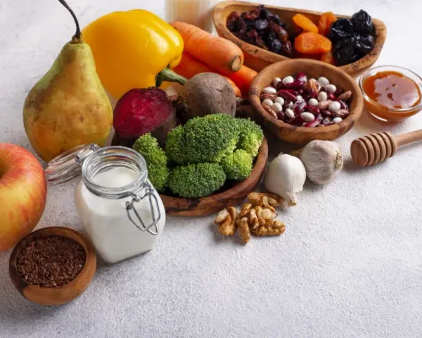 Składniki na zdrową dietę jelitową: jabłko, gruszka, brokuły, buraki, marchew, papryka, fasola, orzechy, czosnek, siemię lniane, jogurt, suszone owoce i miód.