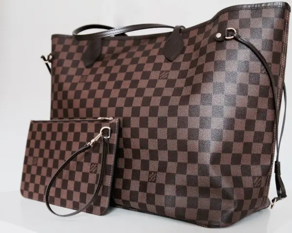 Duża torebka Louis Vuitton w kratkę, obok mniejsza kosmetyczka. Klasyczny wzór Damier Ebene.