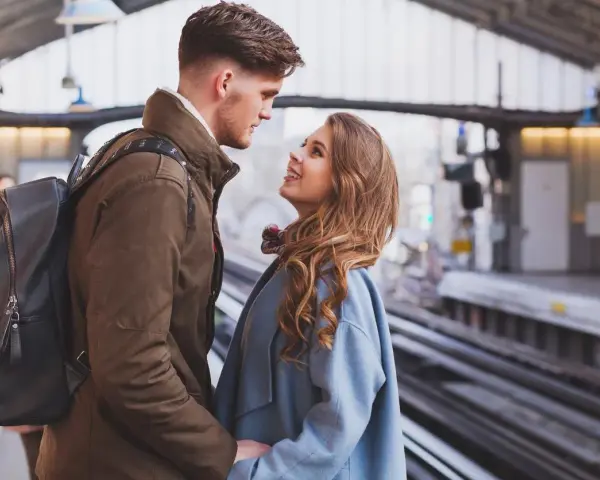 Un couple se regarde avec tendresse sur un quai de gare, un moment où l'on peut se sentir connecté à quelqu'un à distance.