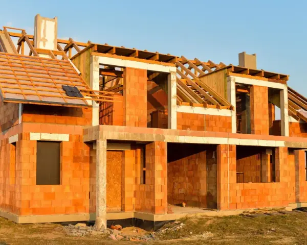 Budowa domu energooszczędnego z cegły ceramicznej. Widoczny szkielet dachu i otwory okienne.