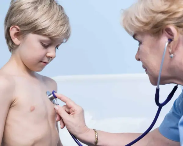 Lekarz osłuchuje klatkę piersiową chłopca, diagnozując zapalenie oskrzeli u dzieci.