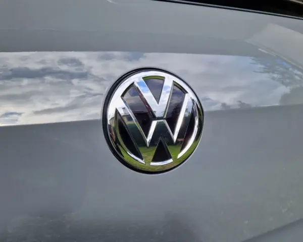 Das VW-Logo auf dem Heck eines grauen Autos. Eine Erklärung zum Fahrzeugdatenträger VW ist hier nicht ersichtlich.