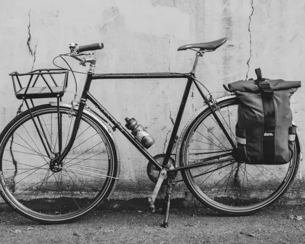 Svart cykel med korg fram och väska bak, redo att montera pakethållare för äventyr.
