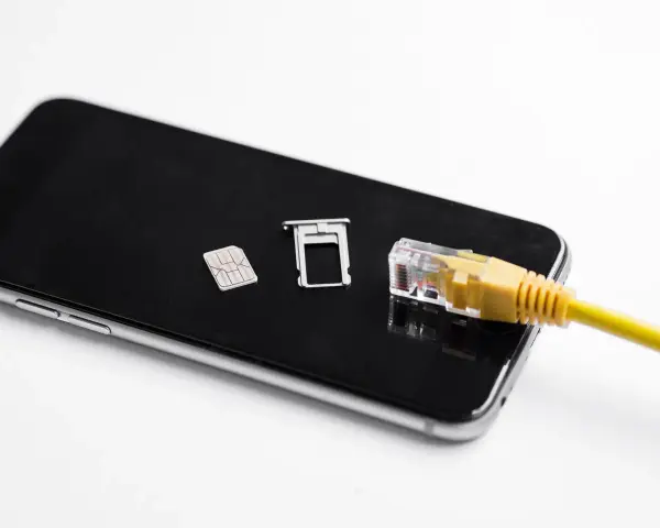 Smartfon z kartą SIM i tacką, podłączony żółtym kablem sieciowym. Możliwość play multisim.