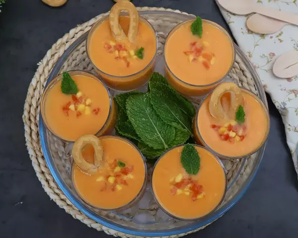 Gazpacho de mango en vasos con trocitos de mango, menta y picos.