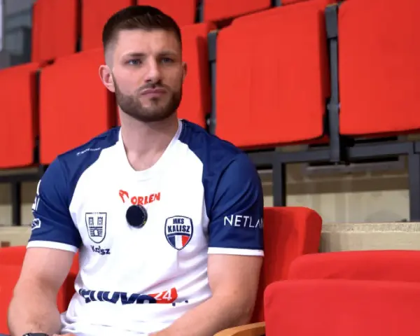Marcel Sroczyk, zawodnik MKS Kalisz, siedzi na czerwonych trybunach.