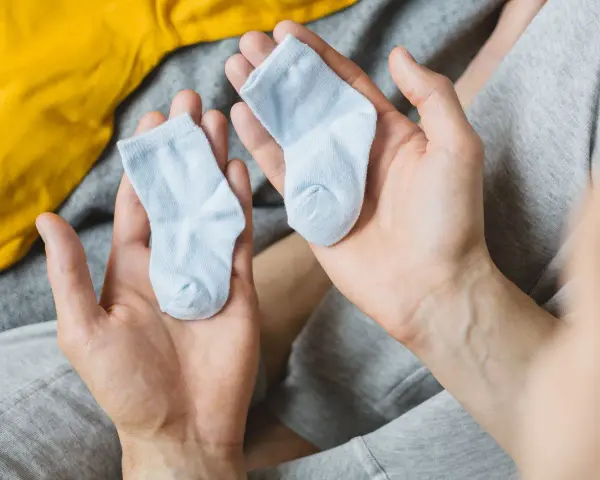 Dwie maleńkie, błękitne skarpetki w dłoniach. Zastanawiasz się, jaki rozmiar skarpetek dla noworodka będzie najlepszy?