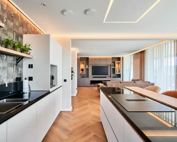 Moderne Küche mit Kochinsel und Wohnbereich. Die indirekte Beleuchtung unterstreicht die Eleganz. Informieren Sie sich über spanndecke kosten für Ihr Zuhause.
