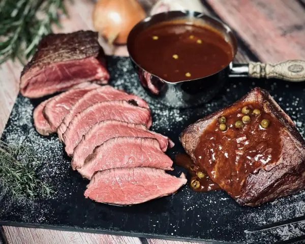 Saftiges Roastbeef mit einer cremigen Pfeffersauce, perfekt für ein festliches pfeffersauce rezept. Dazu frische Kräuter und eine Prise Salz.