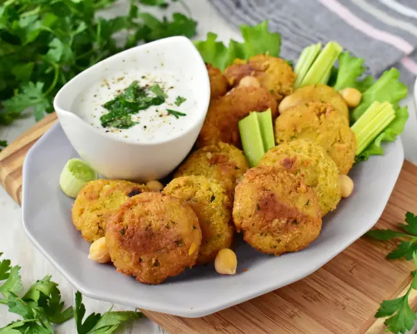 Pyszny falafel przepis na talerzu, podany z sosem jogurtowym, selerem i natką pietruszki. Idealna przekąska!