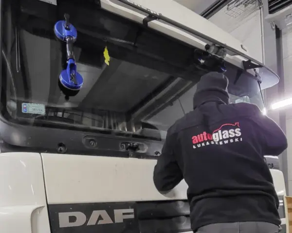 Montaż szyby w traktorze DAF. Pracownik firmy "Autoglass Łukaszewski" używa przyssawek do bezpiecznego osadzenia nowej szyby.