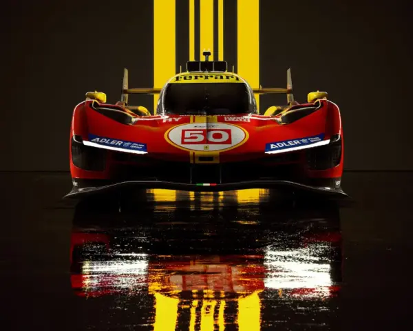 Wyścigowy Ferrari 499P w czerwono-żółtych barwach, z numerem 50, odbija się w mokrej nawierzchni.