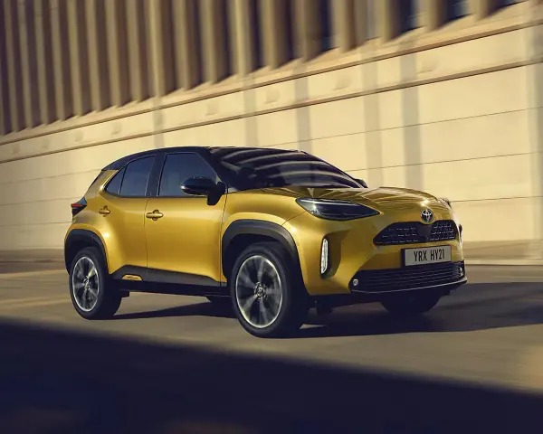 Złoty Toyota Yaris Cross Hybrid w ruchu. Dowiedz się, ile kosztuje Toyota Yaris Hybrid i odkryj jego zalety.