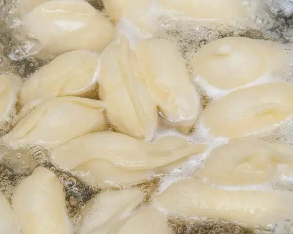 Pierogi gotujące się w bulgoczącej wodzie.