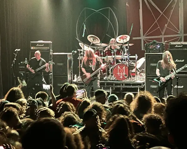 Concert de metal, musiciens sur scène, foule en délire. Le groupe semble prêt à envoyer du lourd, un vrai voyage ad patres pour les fans.