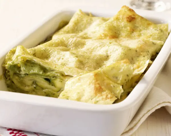Zucchini-Lasagne mit cremiger Füllung und goldbraunen Lasagneplatten in einer weißen Auflaufform.
