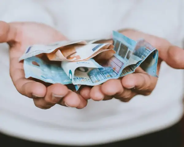 Hände halten zerknitterte Euro-Scheine. Das Geld ist für das geplante **auslandsjahr 3 monate** gedacht.