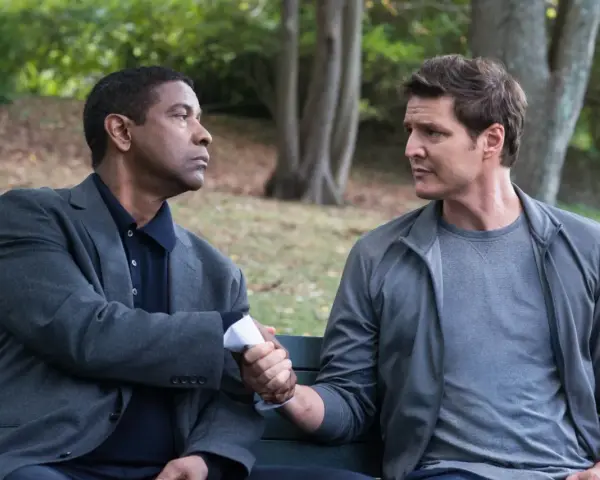 Denzel Washington i Pedro Pascal, obsada "Bez litości 2", siedzą na ławce i ściskają sobie dłonie.