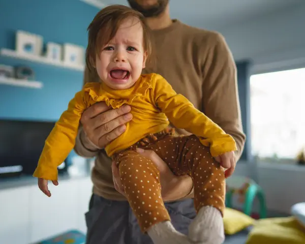 Ein weinendes Kind (2 Jahre) wird von seinem Vater gehalten. Es sagt "Mama weg!" und ist untröstlich.