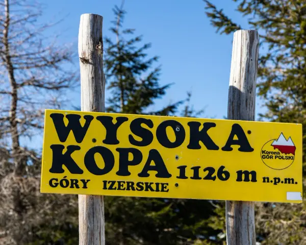 Żółta tablica informuje o szczycie Wysoka Kopa, najwyższym szczycie Gór Izerskich, na wysokości 1126 m n.p.m.