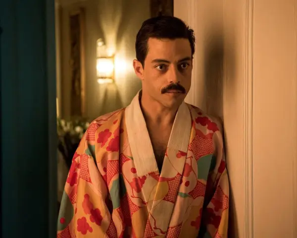 Freddie Mercury w barwnym szlafroku, jakby zrodzony z **bohemian rhapsody**, opiera się o drzwi.