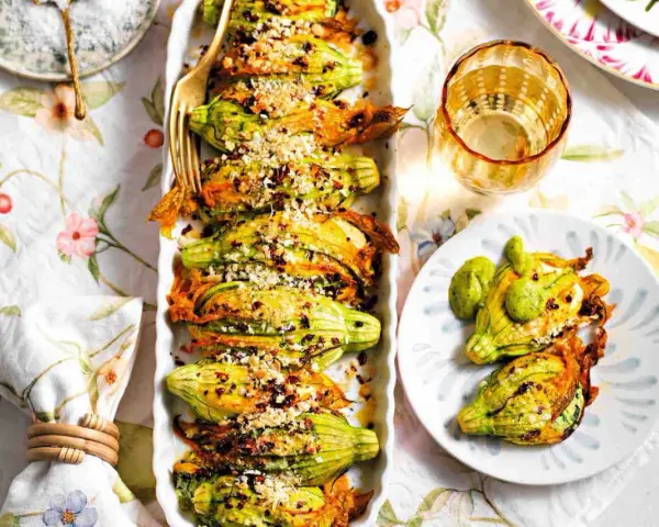 Deliziosi fiori di zucca al forno, ripieni e dorati, serviti su un piatto con un tocco di verde.