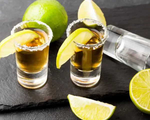 Dwa kieliszki tequili z solą i limonką, gotowe do degustacji. Czas sprawdzić, jak smakuje tequila!