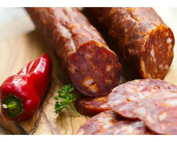 Kawałki pikantnego chorizo, czerwona papryczka i natka pietruszki na desce. Dowiedz się, chorizo co to jest!
