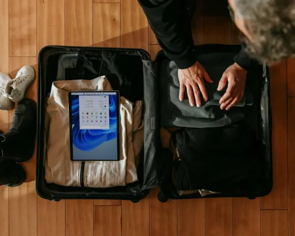 Pakowanie bagażu podręcznego: tablet z systemem Windows, ubrania, buty i kurtka.