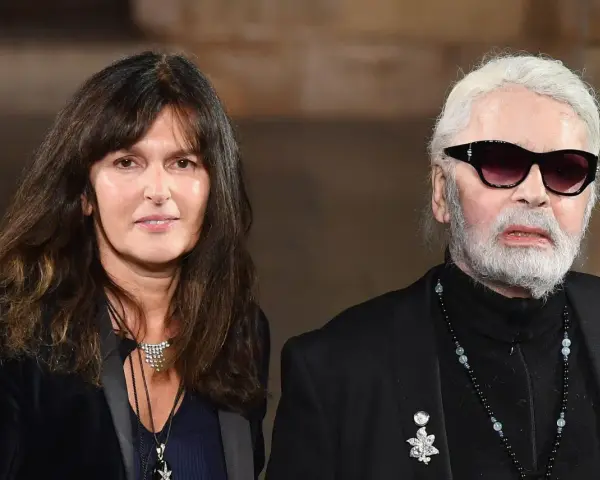 Karl Lagerfeld, iconico stilista Chanel, con una donna dai capelli scuri e un sorriso discreto.