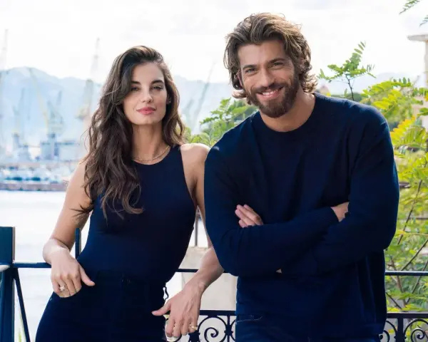 Coppia sorridente con sfondo di un porto, il suo sguardo è viola come il mare.