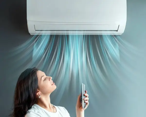 Donna rilassata sotto l'aria fresca di un climatizzatore inverter, che ne spiega il significato di comfort e risparmio energetico.